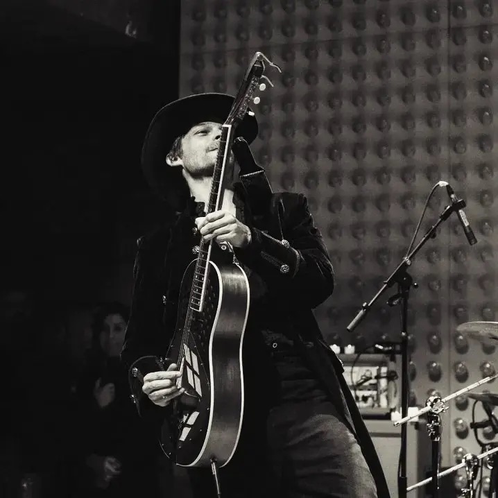 Chris Green raising a resonator guitar to the microphone